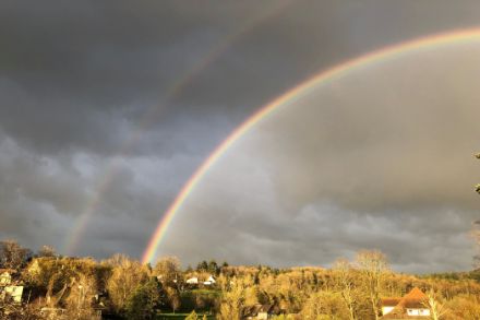 Double arc-en-ciel sur fond de nuages noirs.