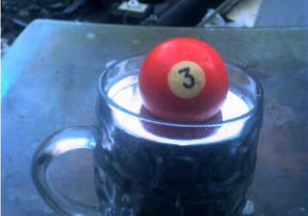 Tension superficielle et force d'Archimède unissent leurs efforts pour permettre à cette boule de billard d'émerger aux trois quarts de ce verre de mercure d'une masse volumique exceptionnelle.