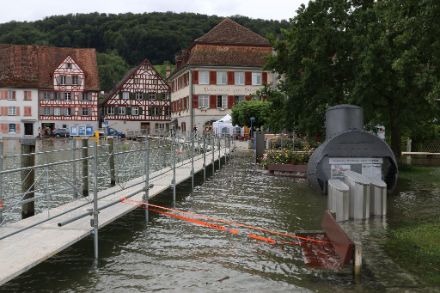 Partie de la rive inondée avec des maisons et une passerelle contre les inondations.