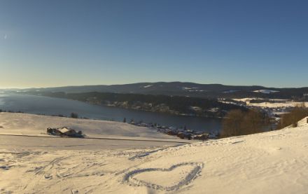 Photo de d'un champs recouvert de neige et du lac de Joux en arrière plan.