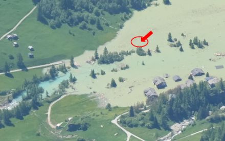 La zone de retenue de la Lonza à Blatten le 30 mai 2025. La station météorologique de Blatten se trouvait à l'endroit marqué en rouge. On distingue encore très vaguement le mât de mesure du vent (flèche rouge).