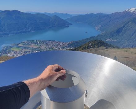 Retrait du filtre au moment de nettoyer le pluviomètre. Pour les stations de montagne, le pluviomètre est entouré par un large pare-vent, visible derrière. Le panorama de Cimetta offre un cadre magnifique pour cette tâche d'entretien périodique. CMReg Sud, N.Gobbi