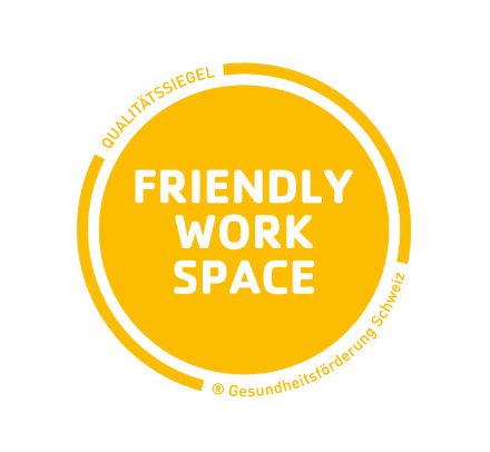 Le logo du label Friendly Workspace se compose d'un cercle jaune. Au centre, Friendly Work Space est écrit en blanc et sur le bord, il est indiqué qu'il s'agit d'un label de qualité de Promotion Santé Suisse