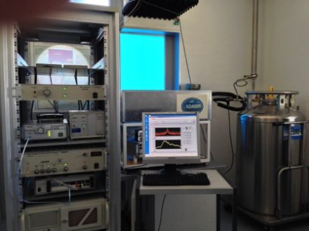 L’image illustre le Radiomètre micro-ondes SOMORA à Payerne. Le système quasi-optique de détection des micro-ondes se situe derrière l'écran d'ordinateur (dans le coffre gris) et mesure les micro-ondes à travers la fenêtre bleue.