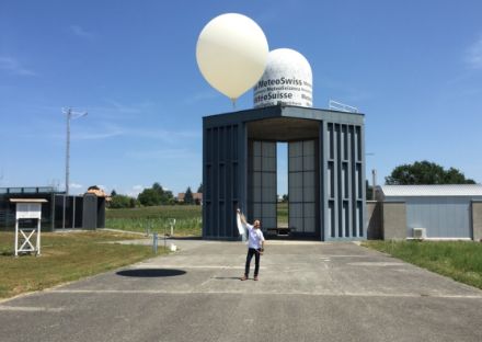 Sur la photo, un homme tient une ficelle au bout de laquelle flotte un ballon météo.