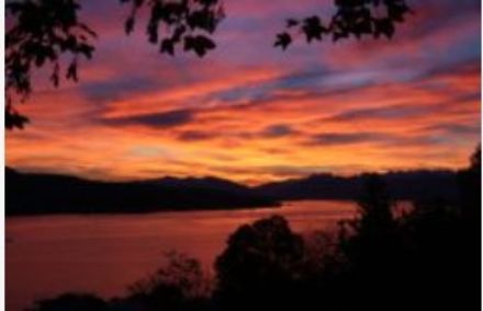 Au premier plan, le lac de Zurich, vue en direction de l'est avec un ciel rouge orangé / légèrement nuageux.