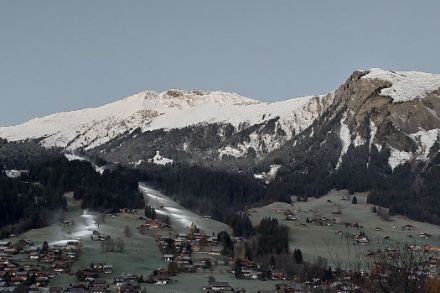 Photo du village de Lenk avec des canons à neige sur les pistes de ski encore vertes.