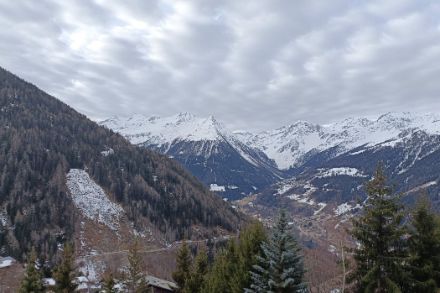 Paysage peu enneigé avec un ciel nuageux. 